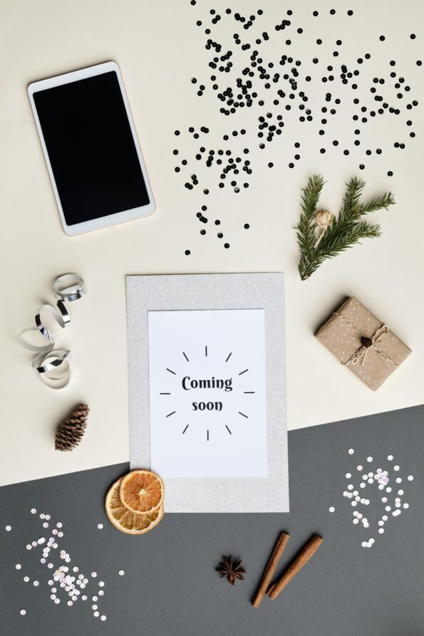 Flatlay of holiday decorations with a digital tablet and 'Coming Soon' card.
